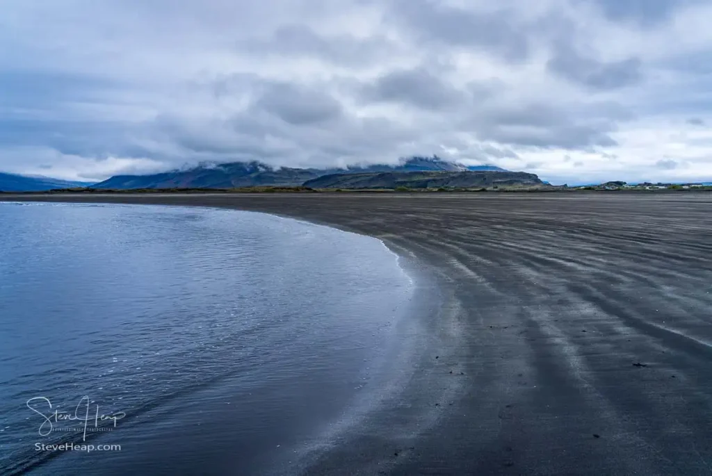 Black sand beach of Bulandsnes in town of Djupivogur in Eastern Iceland waves gently lapping the shoreline