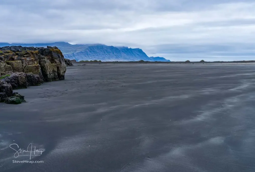 Black sand beach of Bulandsnes in town of Djupivogur in Eastern Iceland with granite rocks framing the view