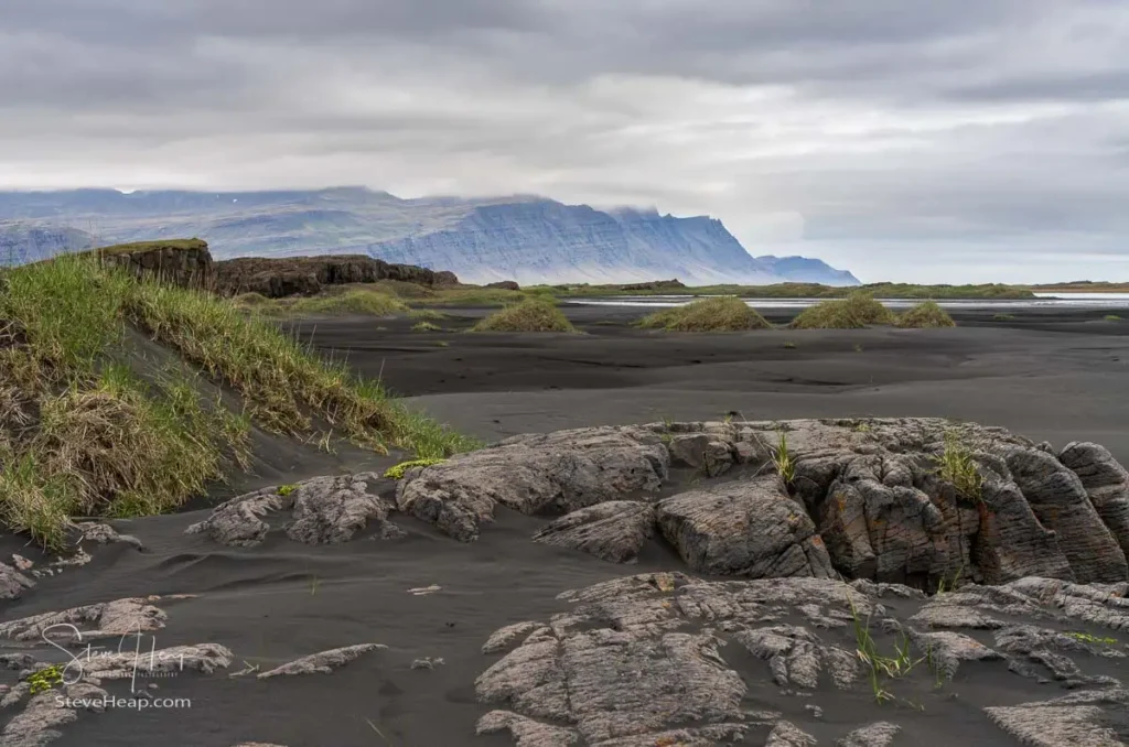 Black sand beach of Bulandsnes in town of Djupivogur in Eastern Iceland with sand dunes framing the view