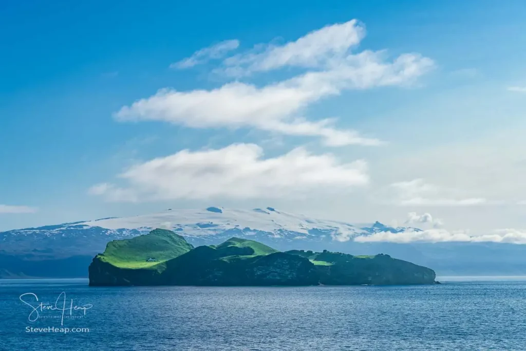 Snow capped mountains behind uninhabited island of Ellidaey Westman Islands in the South of Iceland