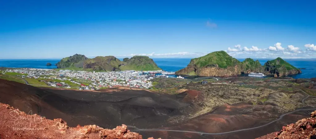 Broad panorama of the view from summit of Eldfell volcano of the town and harbor with cruise ship anchored on the Island of Heimaey in Iceland