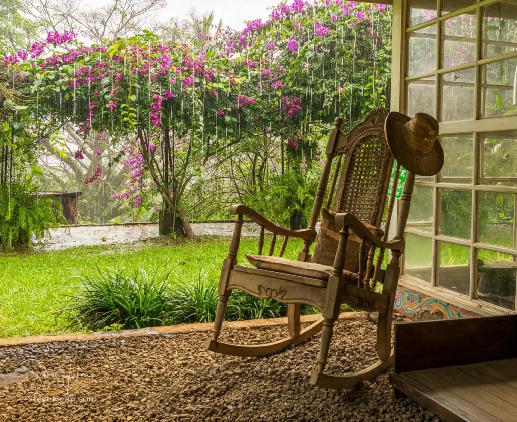 Carved wooden rocking chair with pouring rain streaming off the roof