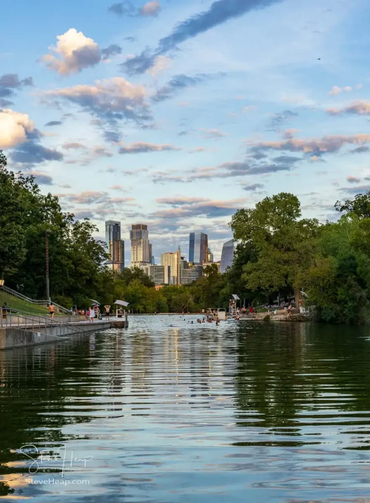 Swimmers in the Barton Springs swimming pool with Austin skyline at sunset