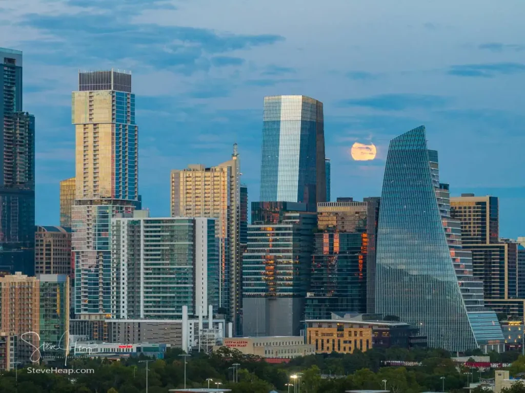 Aerial drone view of the Austin Texas skyline as the full harvest moon is seen rising by the office buildings. Zilker Park in the foreground