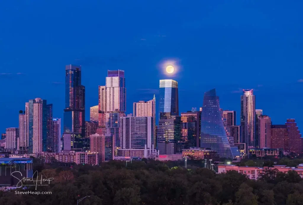 Aerial drone view of the Austin Texas skyline as the full harvest moon is seen rising by the office buildings. Zilker Park in the foreground.