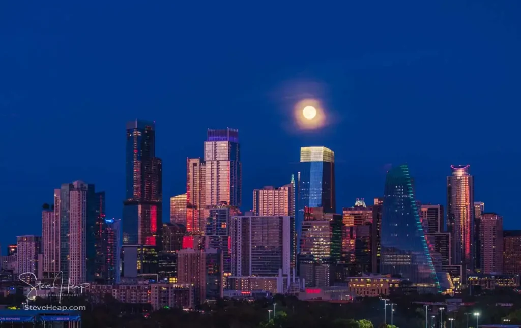 Aerial drone view of the Austin Texas skyline as the full harvest moon is seen rising by the office buildings. Zilker Park in the foreground.