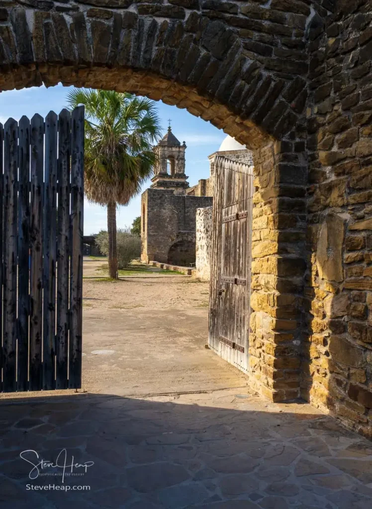 Mission San Jose near San Antonio with church seen through the stone entrance archway and wooden gate