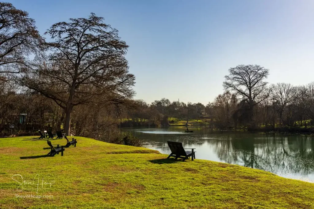 Restful chairs on lawn by the calm Guadalupe river near New Braunfels in Texas in the late winter