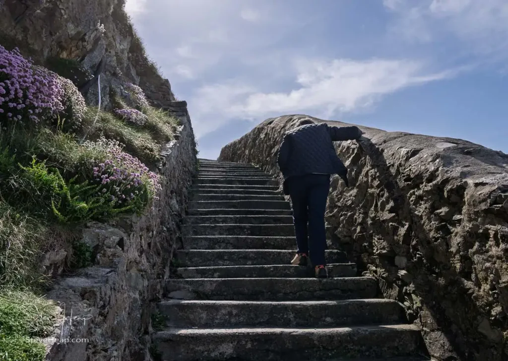 Senior woman climbing the steps up from South Stack lighthouse on Anglesey