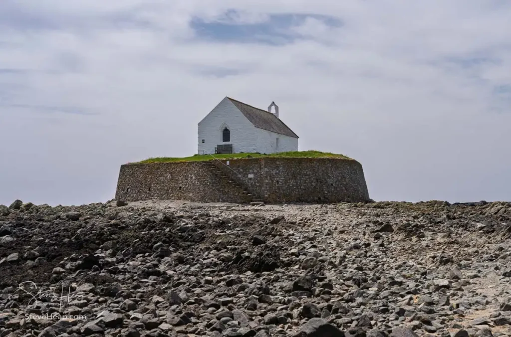 Eglwys Cwyfan, the Church in the Sea, sitting on its walled tidal island on a rocky Anglesey beach