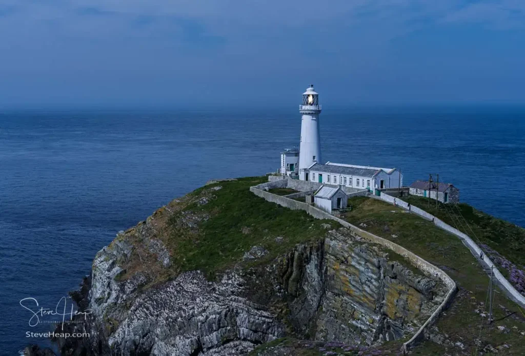 South Stack Lighthouse glowing at twilight against the dark Irish Sea