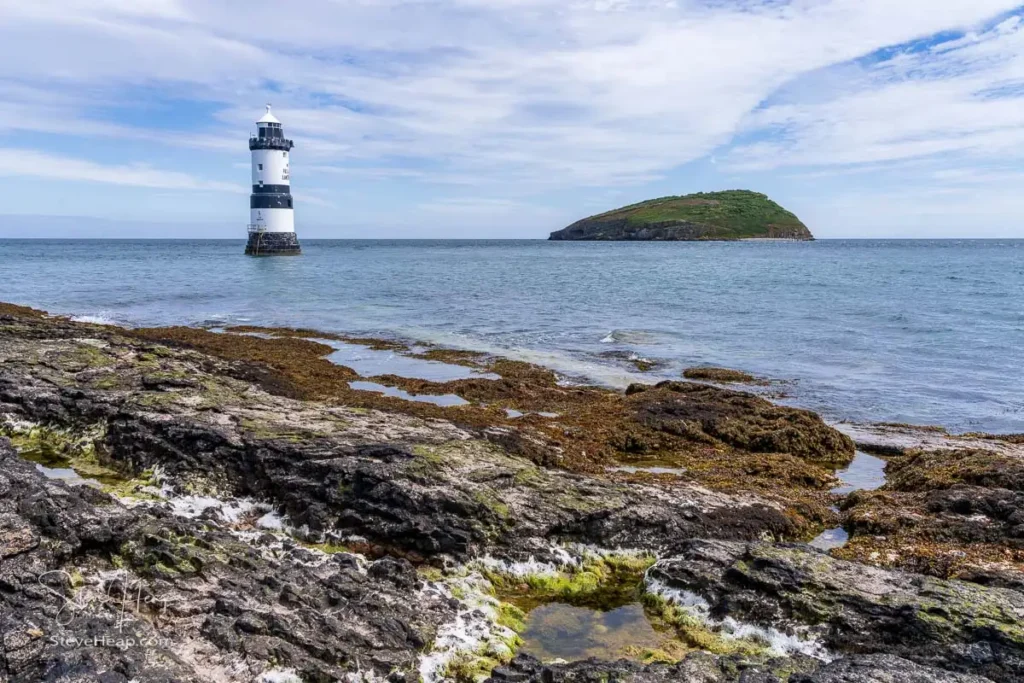 Black-and-white striped Trwyn Du Lighthouse at Penmon Point with Puffin Island in the distance