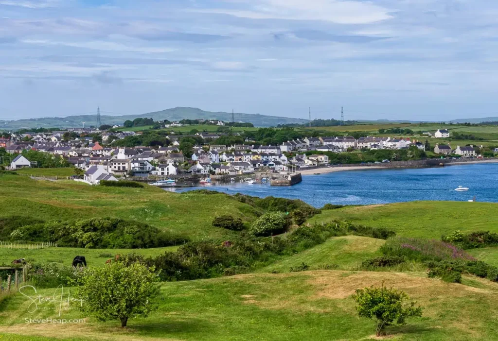 High-angle view overlooking Cemaes Bay village and crescent harbor under a soft sky in Anglesey, Wales