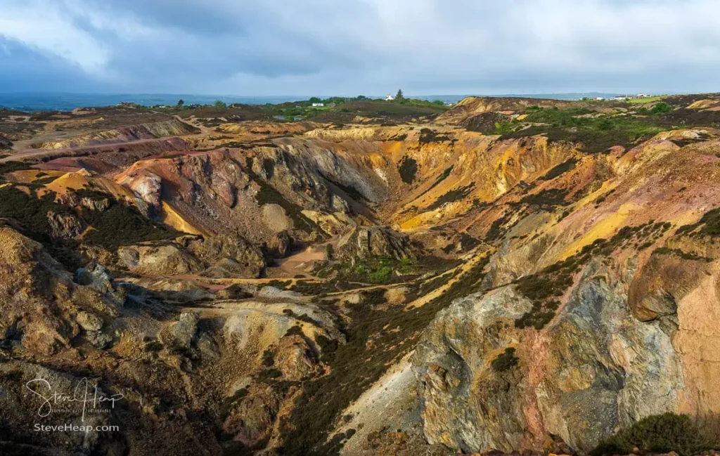 Vast, colorful open-cast copper mine crater with orange and ochre rock faces at Mynydd Parys