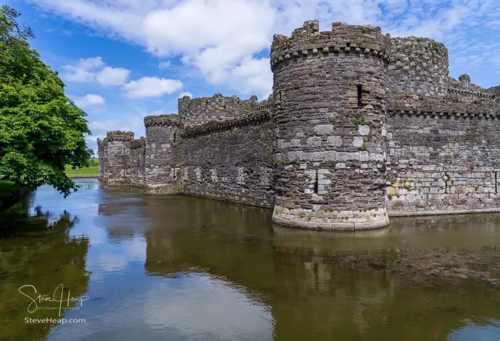 Thick stone outer walls and water-filled moat of medieval Beaumaris Castle